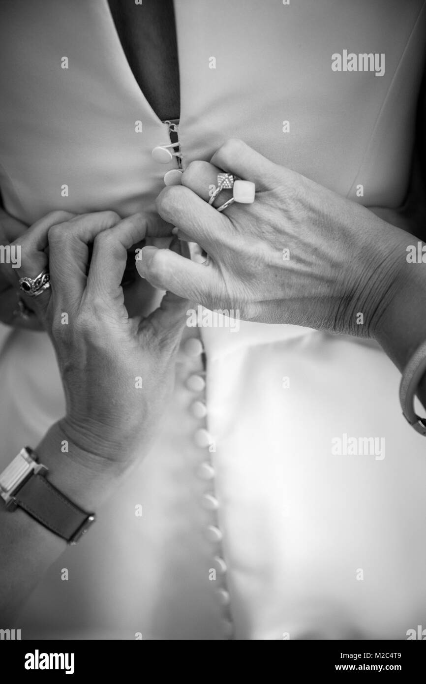 Person buttoning bride's wedding dress, close-up, black and white Stock Photo