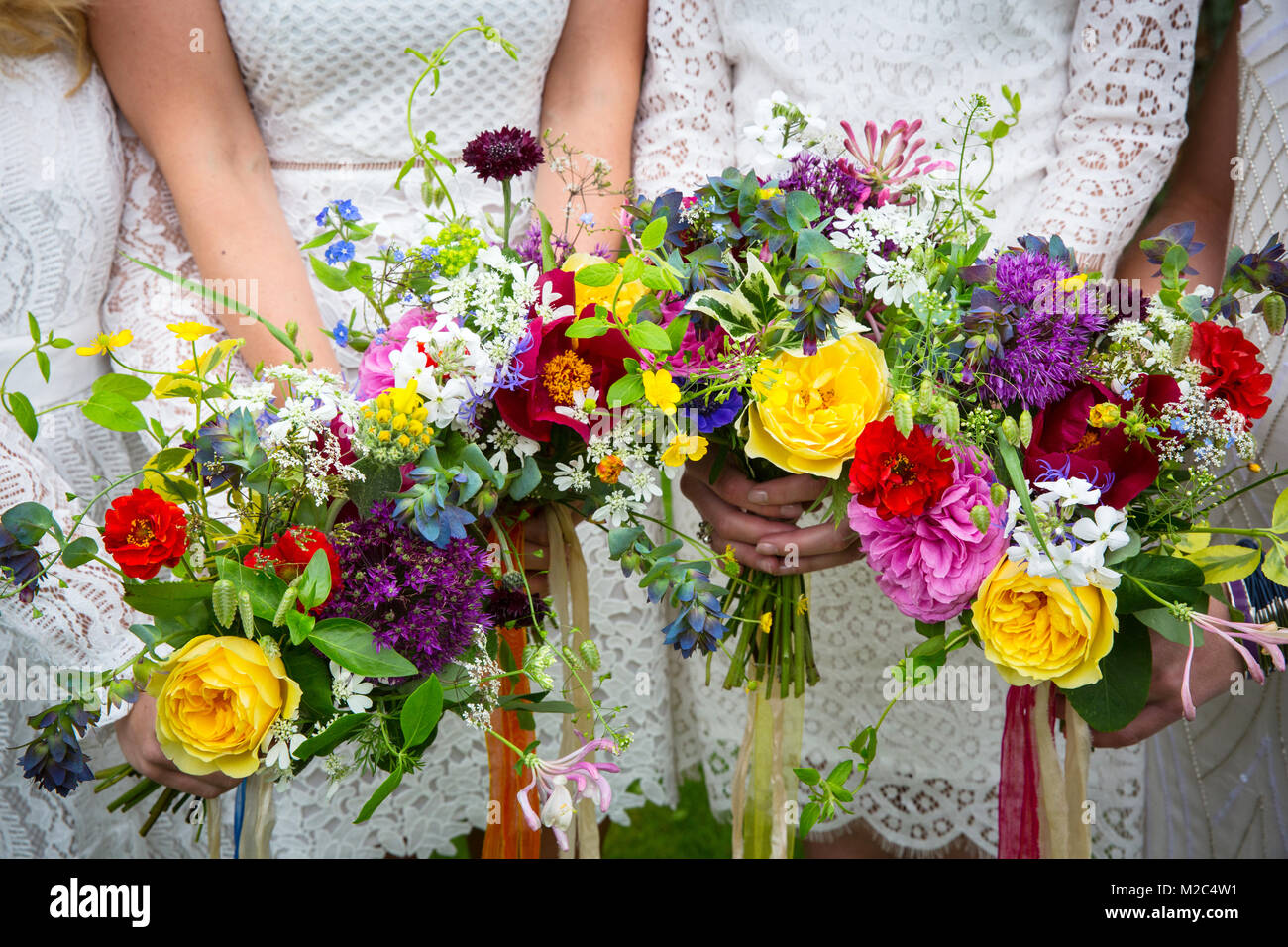 Bridesmaids holding colourful bouquets of flowers, mid section, close-up Stock Photo