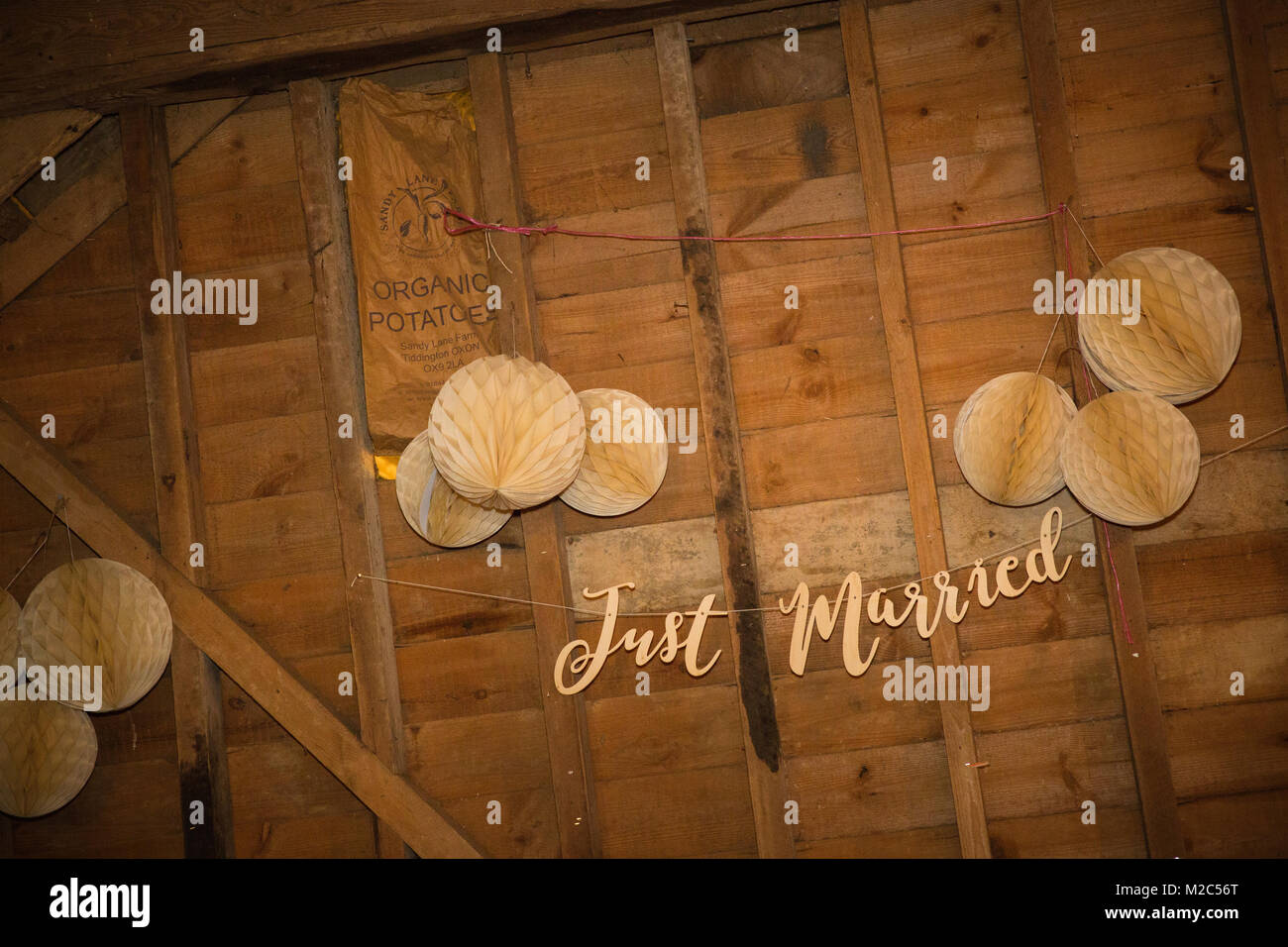 Paper decorations hanging in barn with 'Just Married' sign Stock Photo