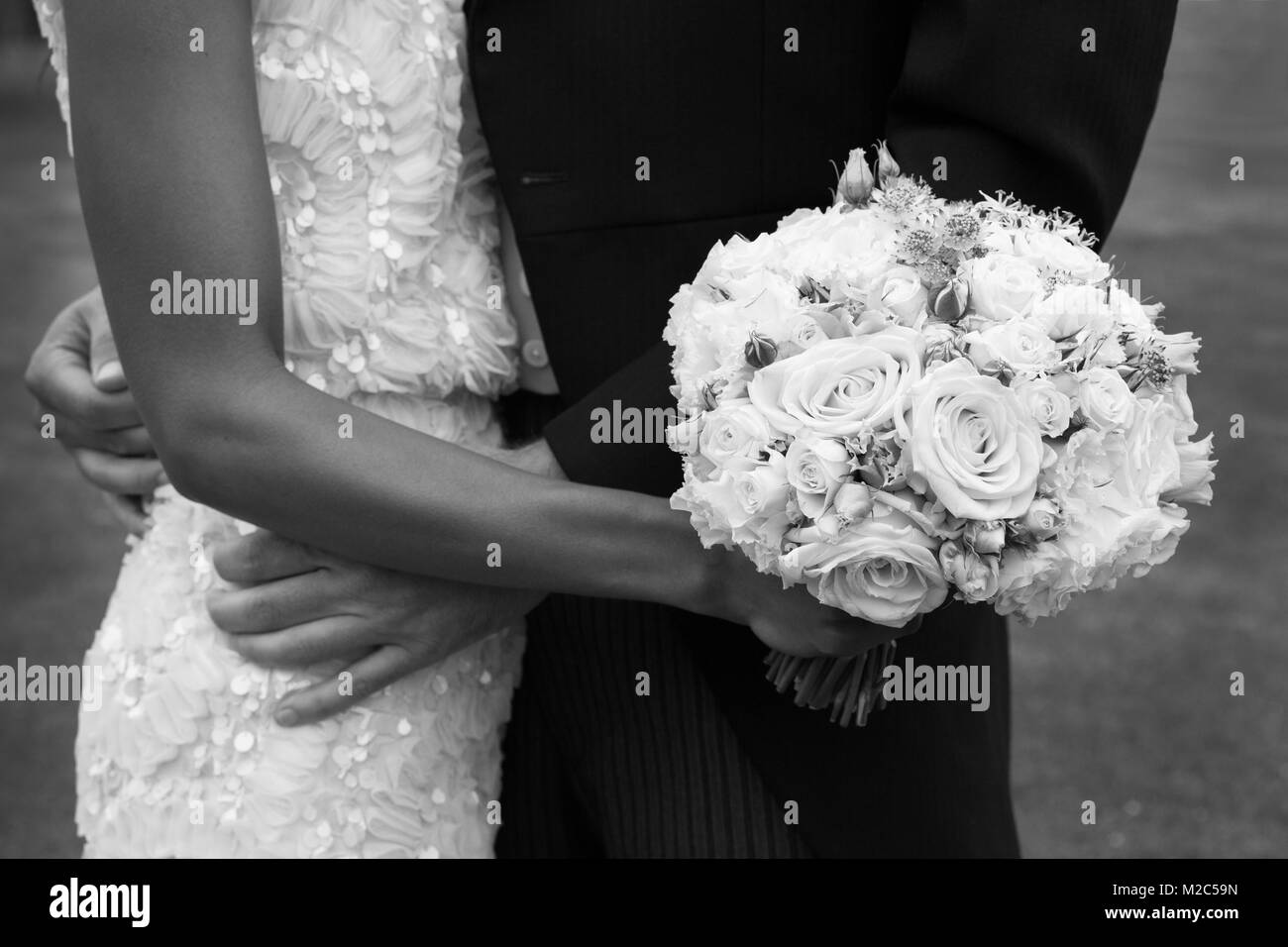 Bride and groom, face to face, bride holding wedding bouquet, mid section, black and white Stock Photo