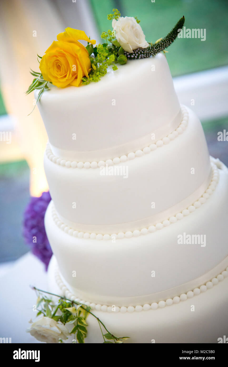 Fresh flowers on top of three tiered celebration cake Stock Photo