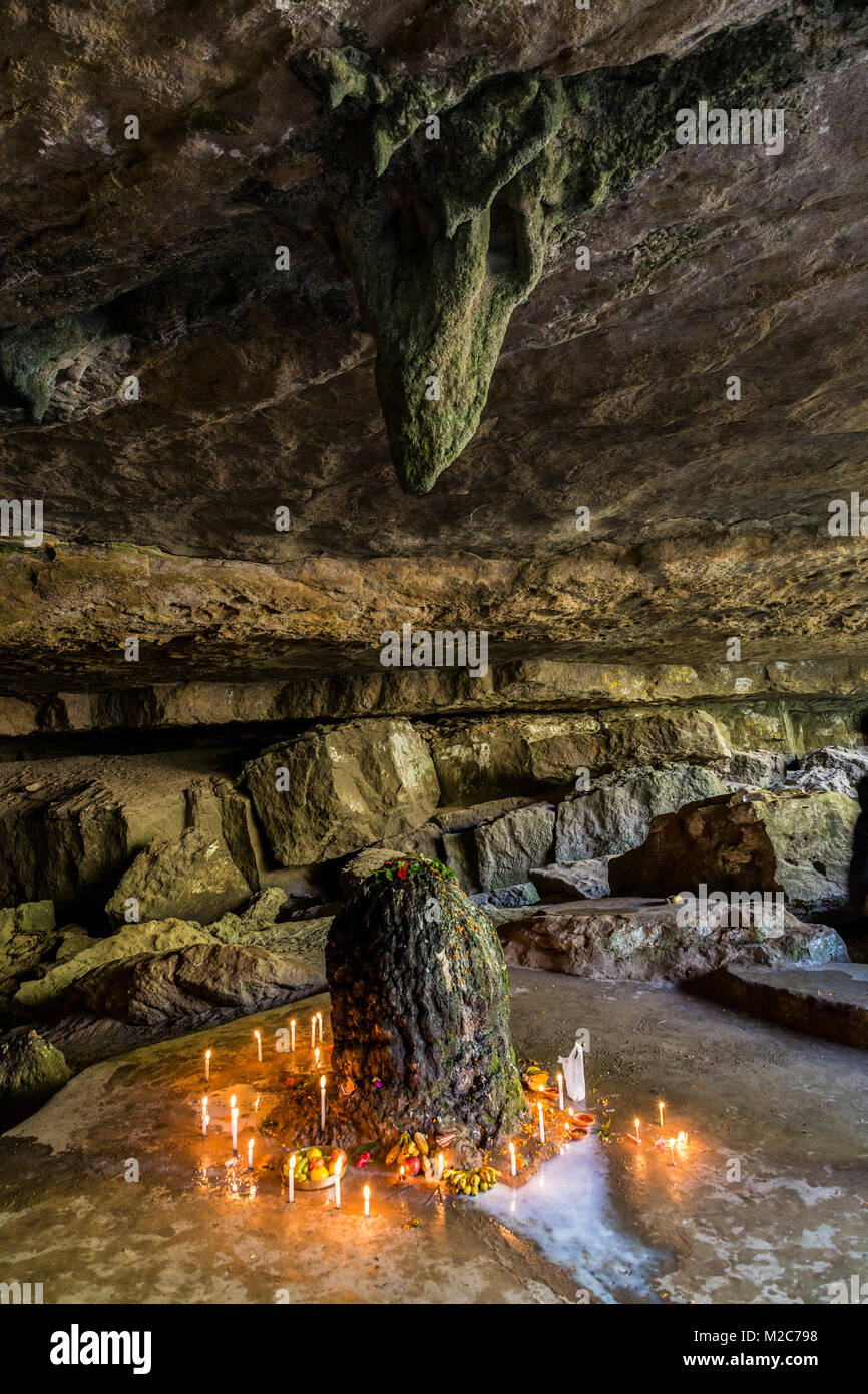 Candles and offerings around stalagmite in holy cave, Mawjymbuin Cave
