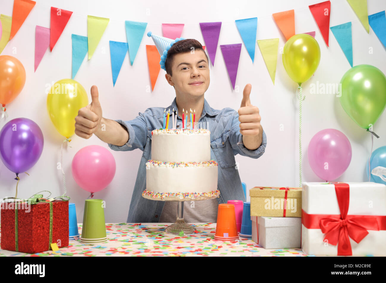 Teenage boy with a birthday cake holding his thumbs up Stock Photo