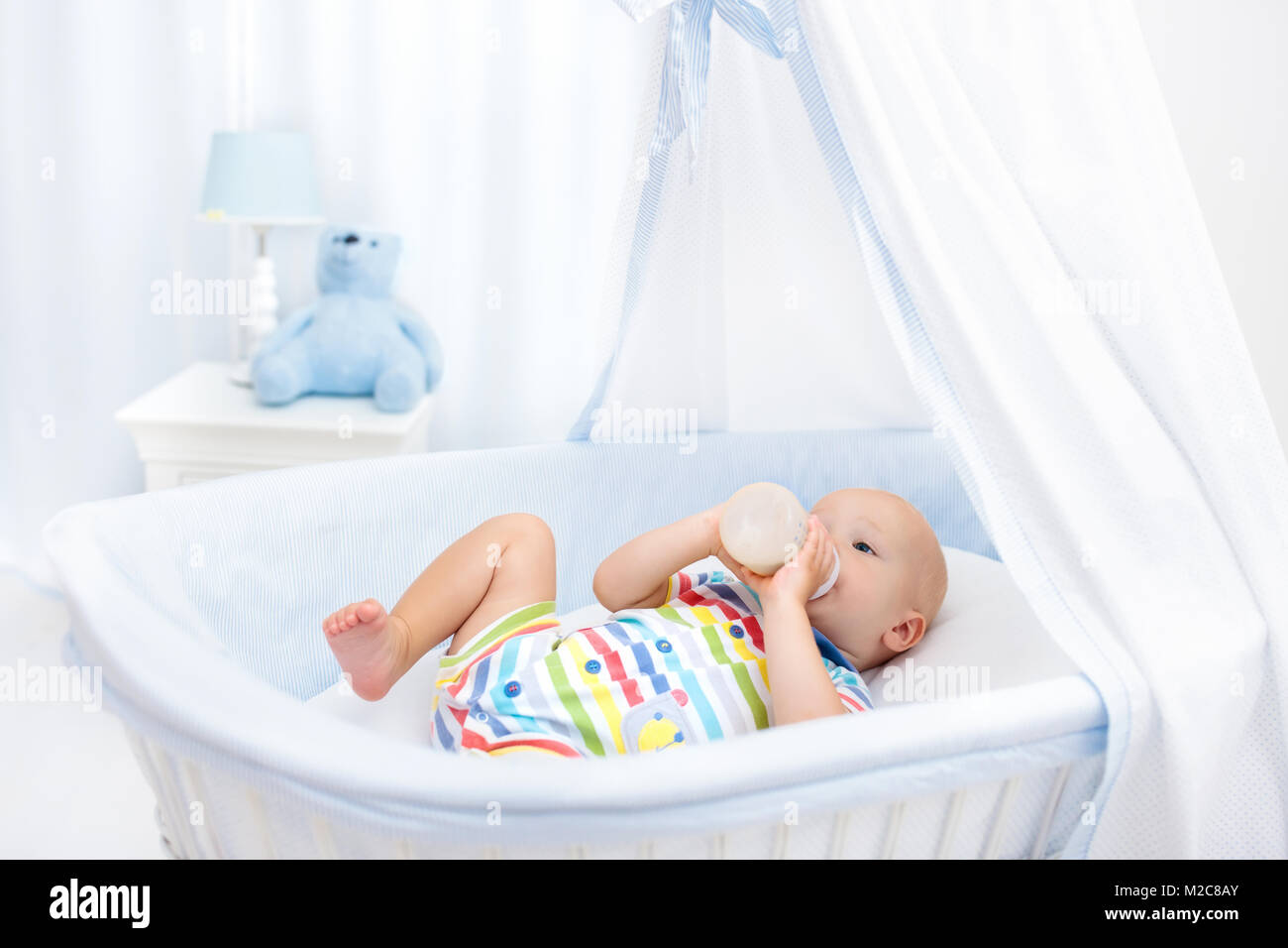 Baby Drinking Milk In White Crib Infant Boy With Formula Bottle