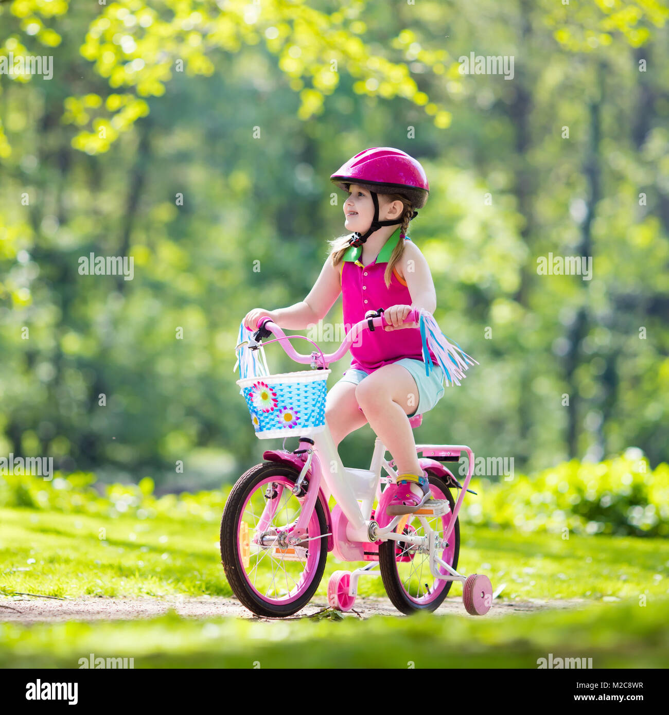 Child riding bike. Kid on bicycle in sunny park. Little girl enjoying