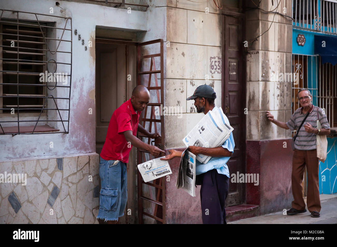 A person selling a newspaper to a local in Havana, Cuba. Stock Photo