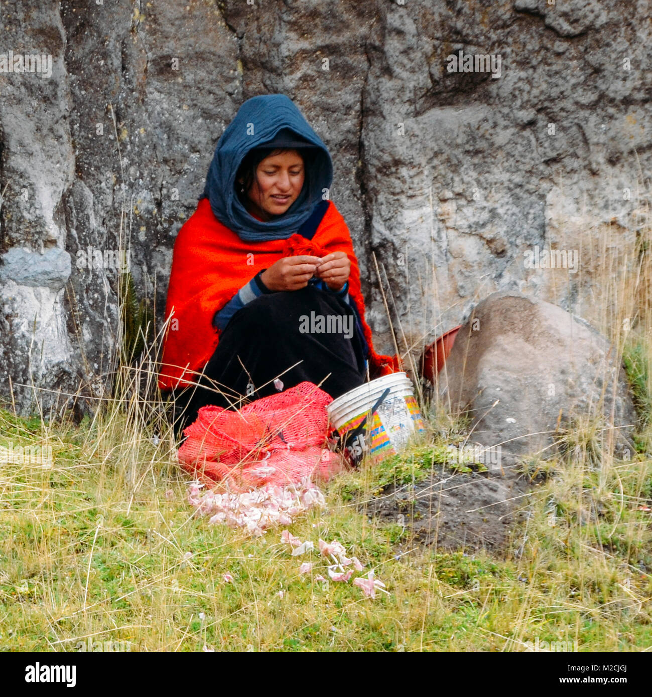 Chimborazo, Ecuador, December 20, 2017: Traditionally dressed Ecuadorian woman peel garlic on the side of a road Stock Photo