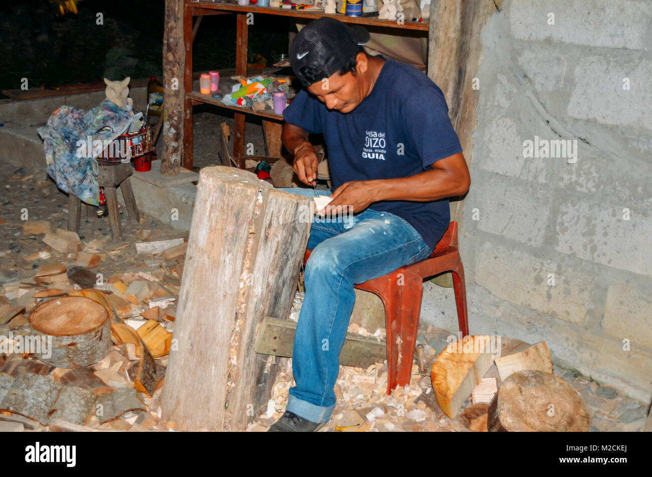 Local Quechua Ecuadorian indigenous man chipping away at a piece Stock Photo
