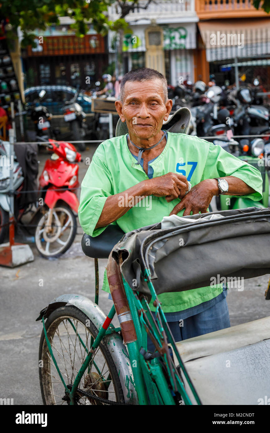 Friendly local Cambodian cycle rickshaw driver from Cyclo City Tour in a green shirt in Phnom Penh, capital city of Cambodia, south-east Asia Stock Photo