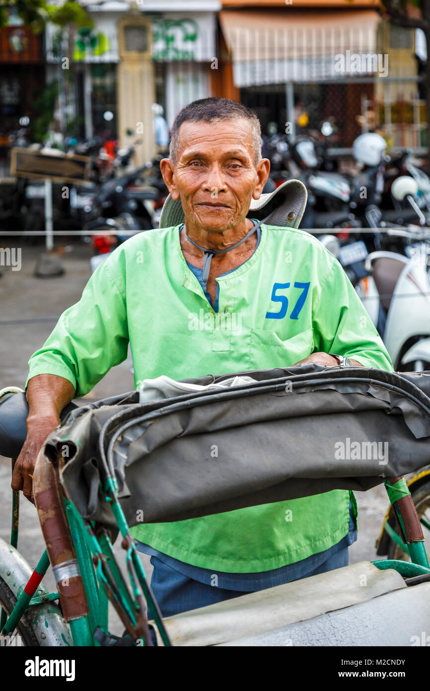 Friendly local Cambodian cycle rickshaw driver from Cyclo City Tour in a green shirt in Phnom Penh, capital city of Cambodia, south-east Asia Stock Photo