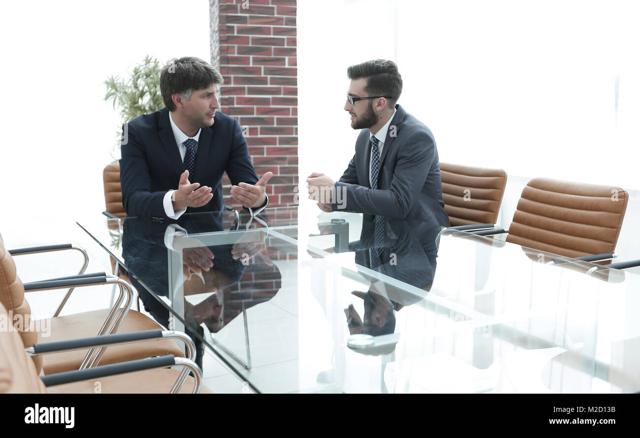 Two businessmen discussing tasks sitting at office table Stock Photo ...