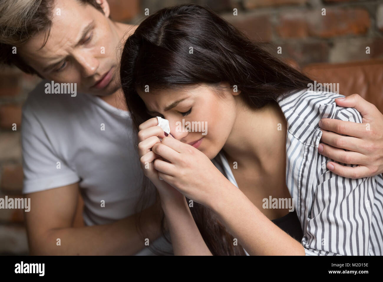 Man comforting crying sad woman, friend consoling girl in tears Stock Photo