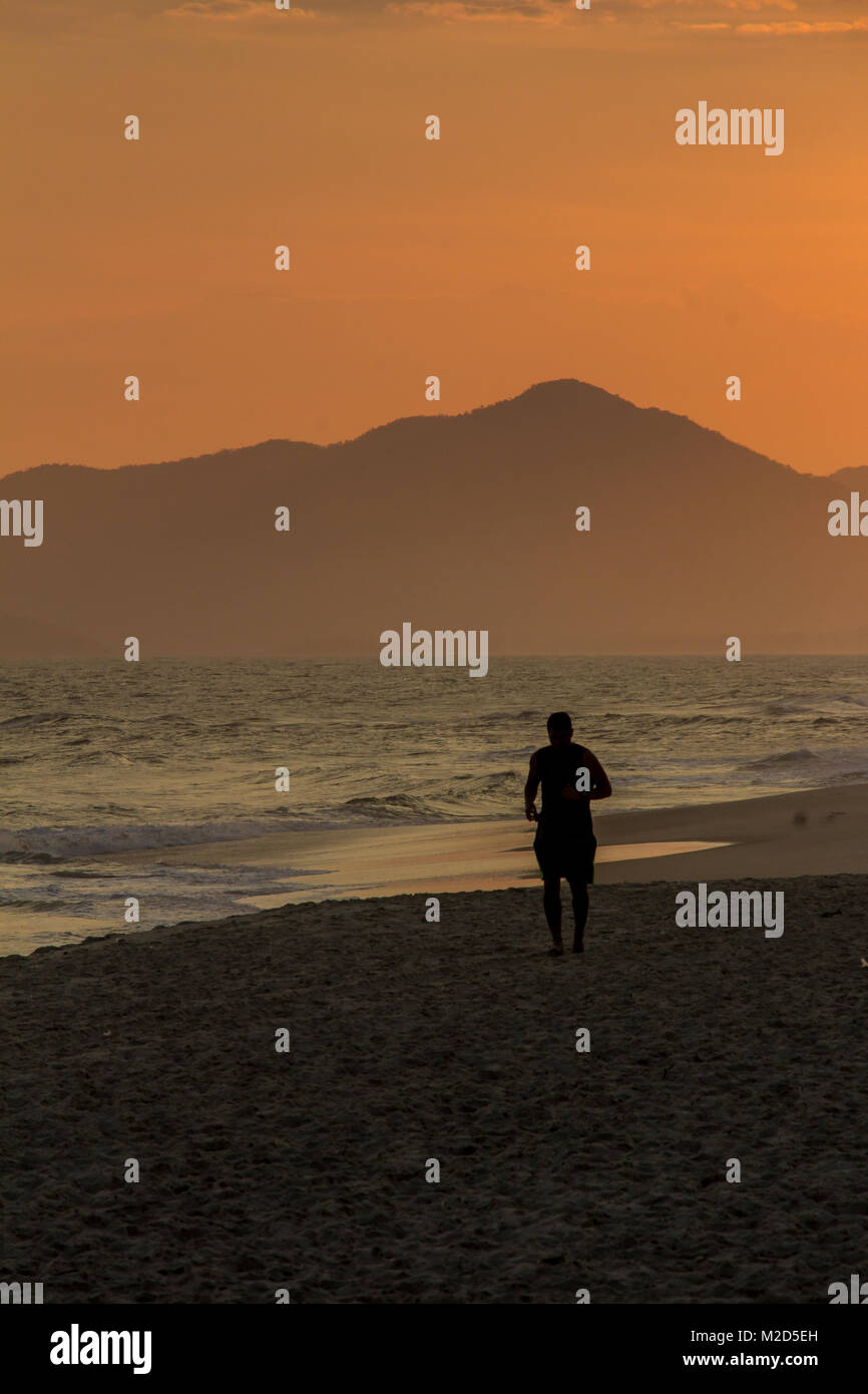 Silhouette of a man running on the beach during sunset Stock Photo - Alamy