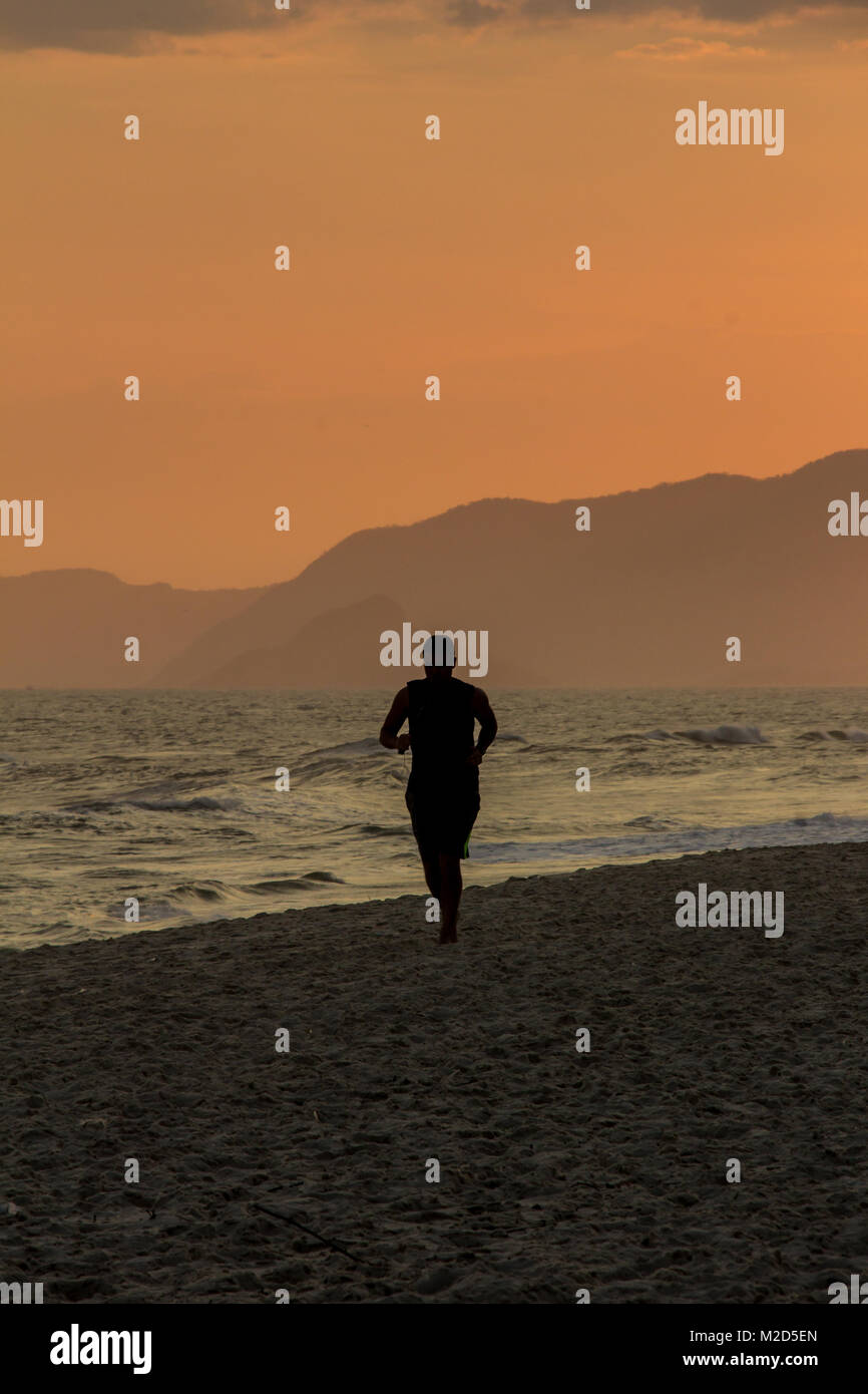 Silhouette of a man running on the beach during sunset Stock Photo - Alamy