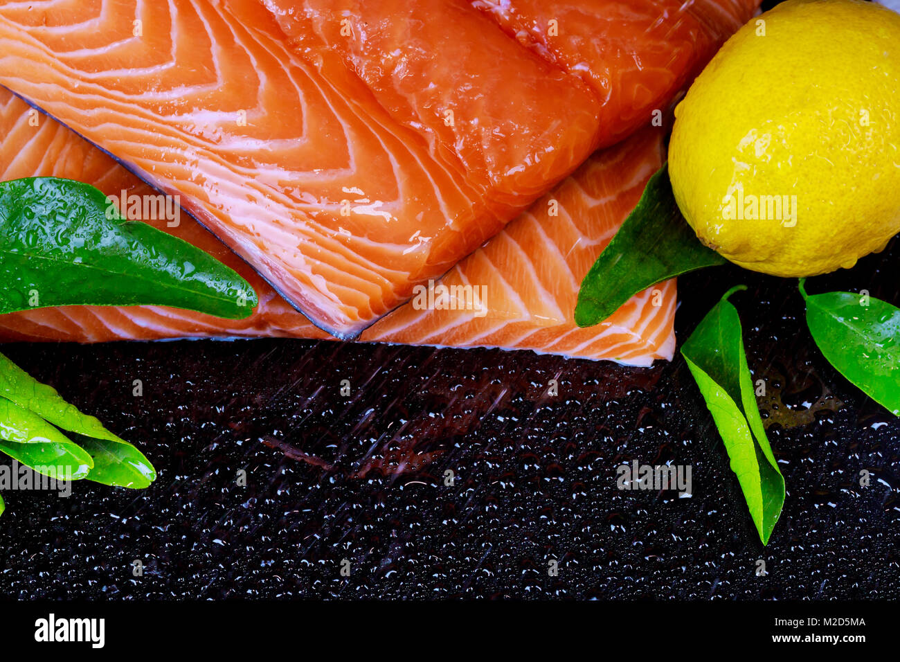 Fresh raw salmon fish fillet on black background and lemon Stock Photo ...