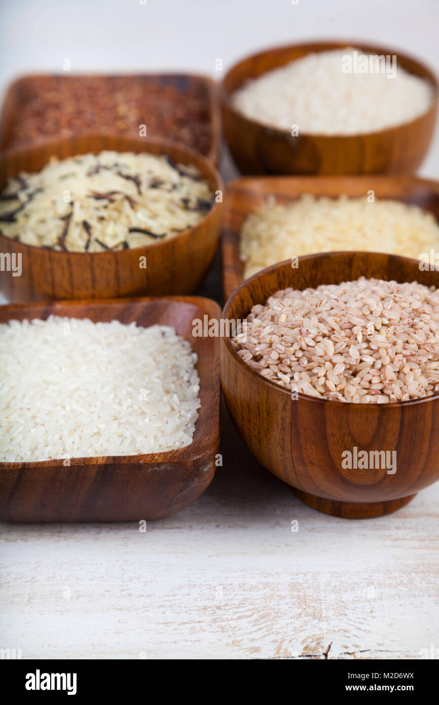 Six bowls with different varieties of rice on a wooden background ...