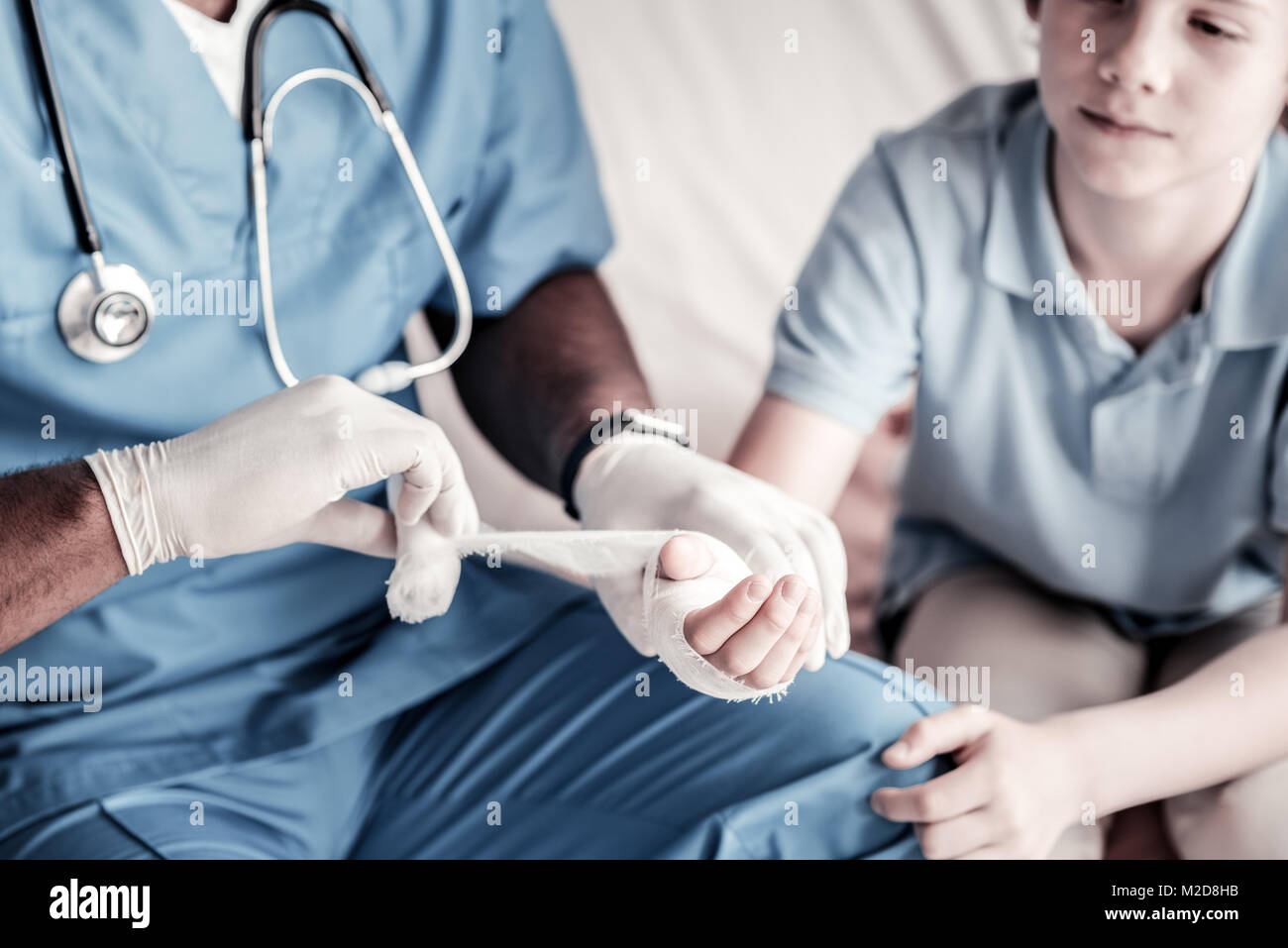 Close up of doctor bandaging hand of teenage boy Stock Photo