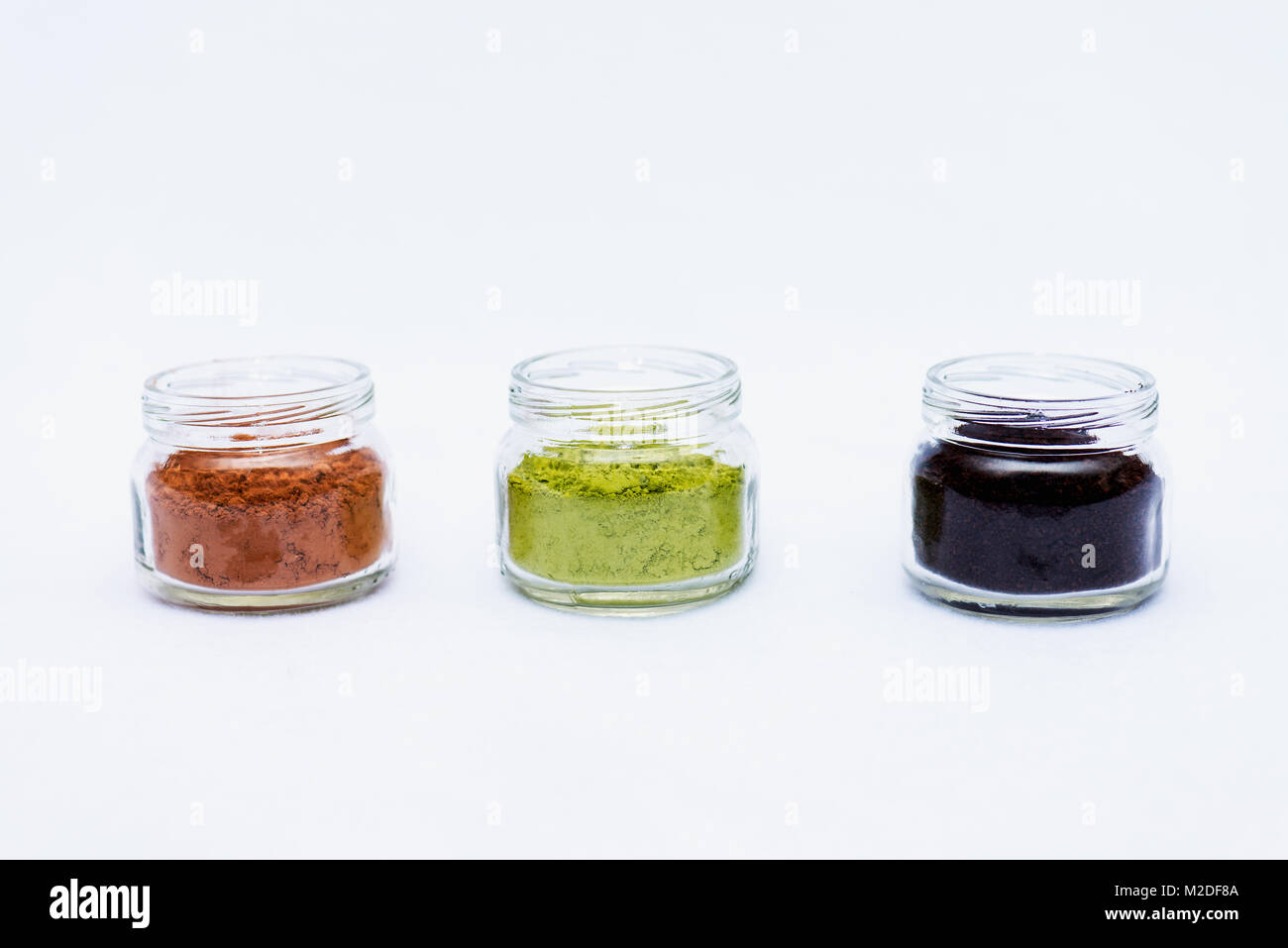 Ground cocoa, coffee and matcha in glass jars, natural antioxidants Stock Photo