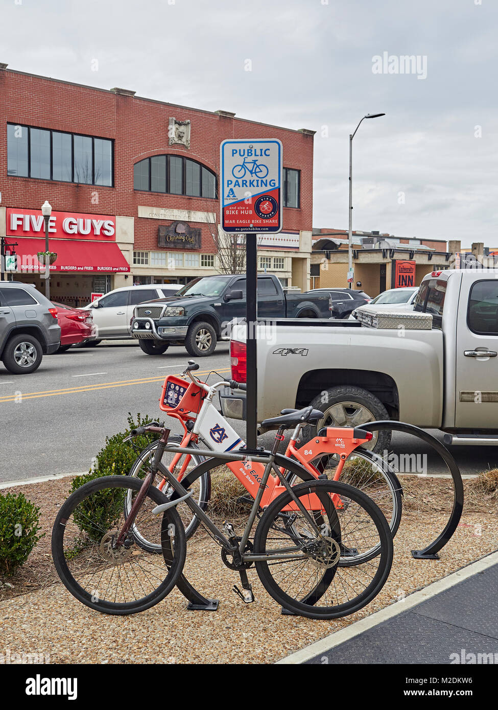Public bicycle parking stand with two bicycles parked, one being a ride share bike from Auburn University, known as a bike hub in Auburn Alabama USA. Stock Photo
