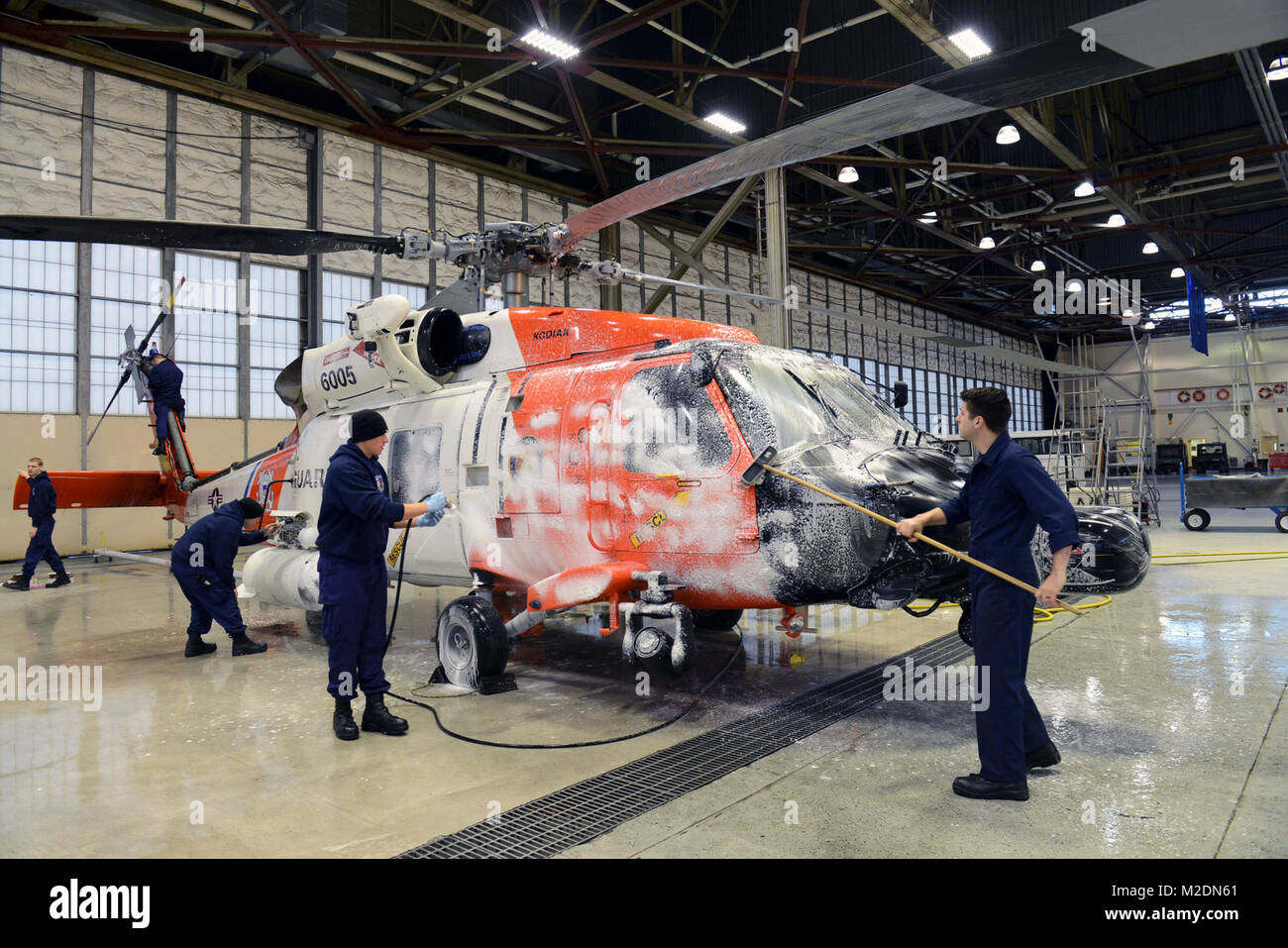 Coast Guard Air Station Kodiak aviators wash an MH-60 Jayhawk helicopter Jan. 3, 2018, in Hangar 3 at Air Station Kodiak, Alaska. Routine maintenance by washing an aircraft removes salt water residue, dirt and debris and ensures a reduction in corrosion. U.S. Coast Guard Stock Photo