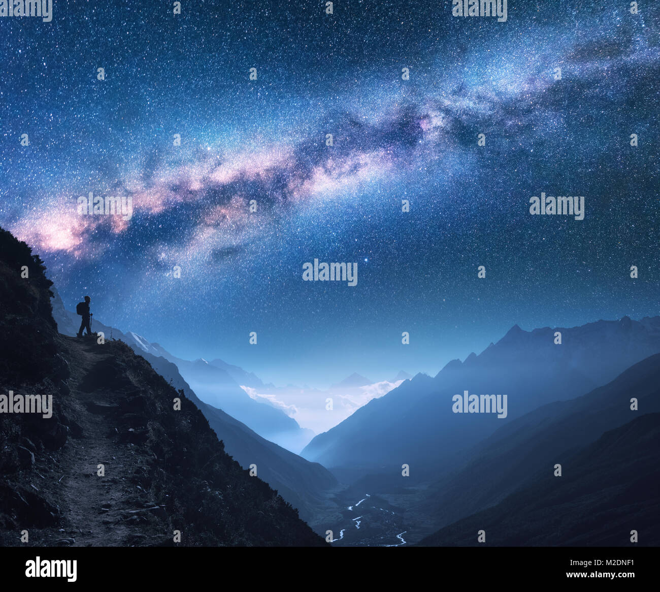 Space with Milky Way, girl and mountains. Silhouette of standing woman on the mountain peak, mountains and starry sky at night in Nepal. Sky with star Stock Photo