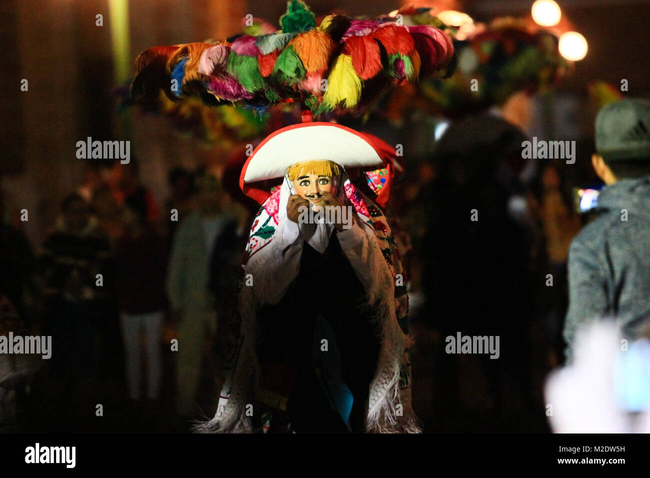 Horizontal photo of a Carnival scene, a dancer wearing a traditional mexican folk costume and mask looking right into the camera Stock Photo