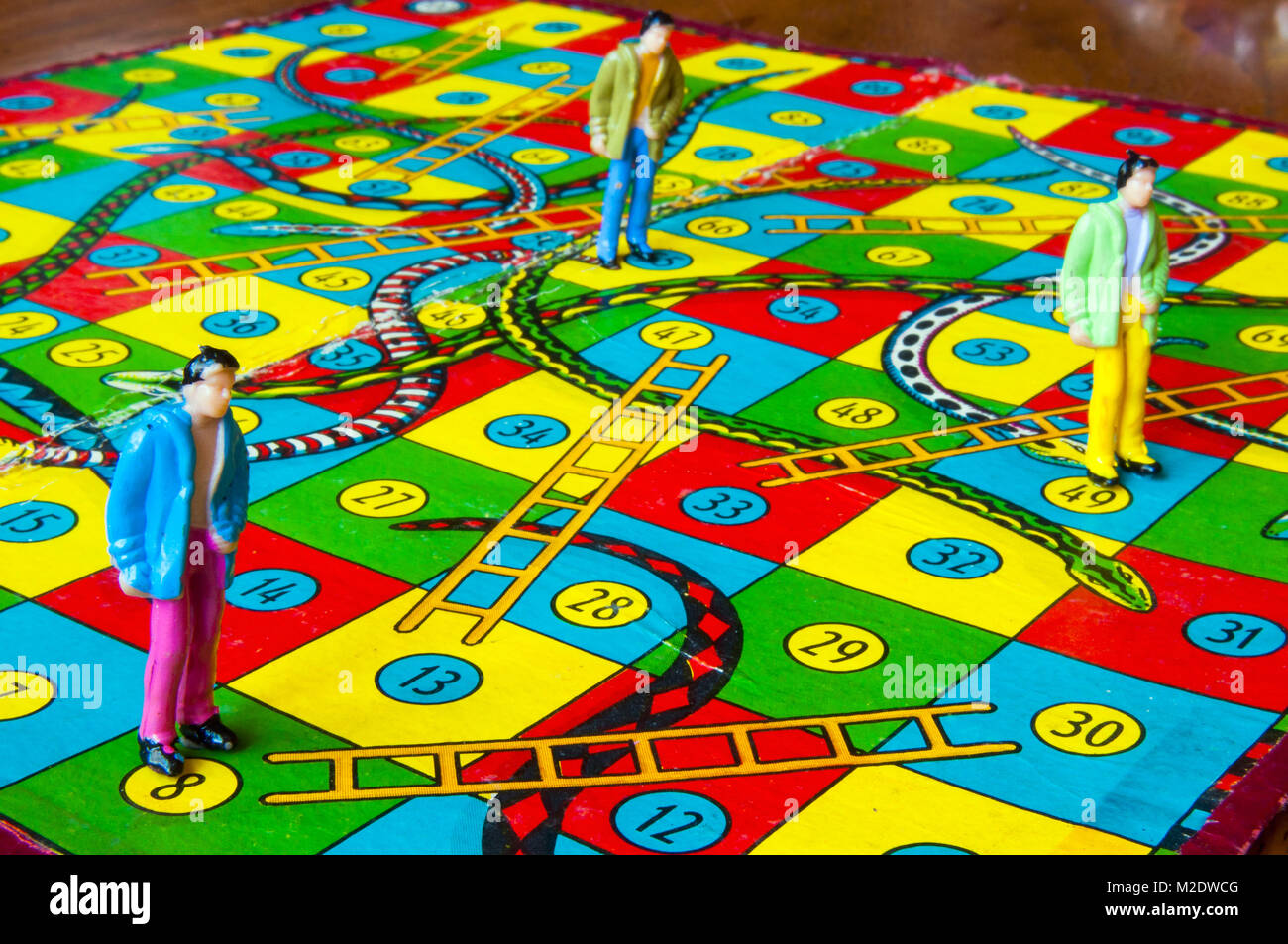 Retro snakes and ladders board with miniature human figures in studio setting, Melbourne, Australia Stock Photo