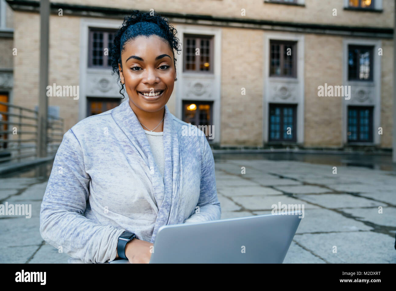 Portrait of smiling Black woman using laptop outdoors Stock Photo