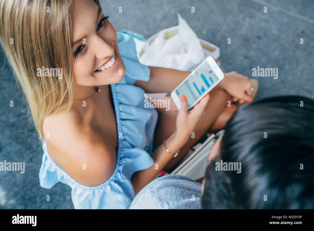 Smiling Caucasian woman texting on cell phone near man Stock Photo