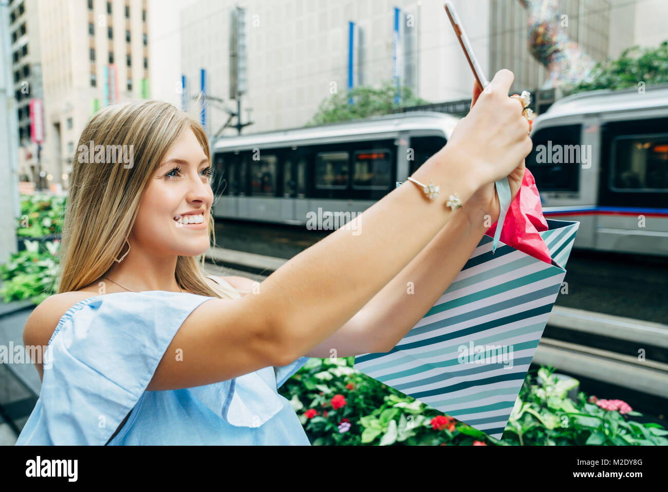 Caucasian woman with shopping bag posing for cell phone selfie Stock Photo