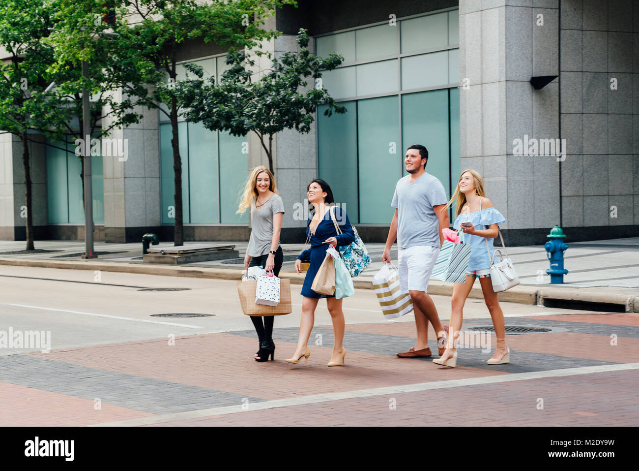 Friends crossing street in city carrying shopping bags Stock Photo Alamy
