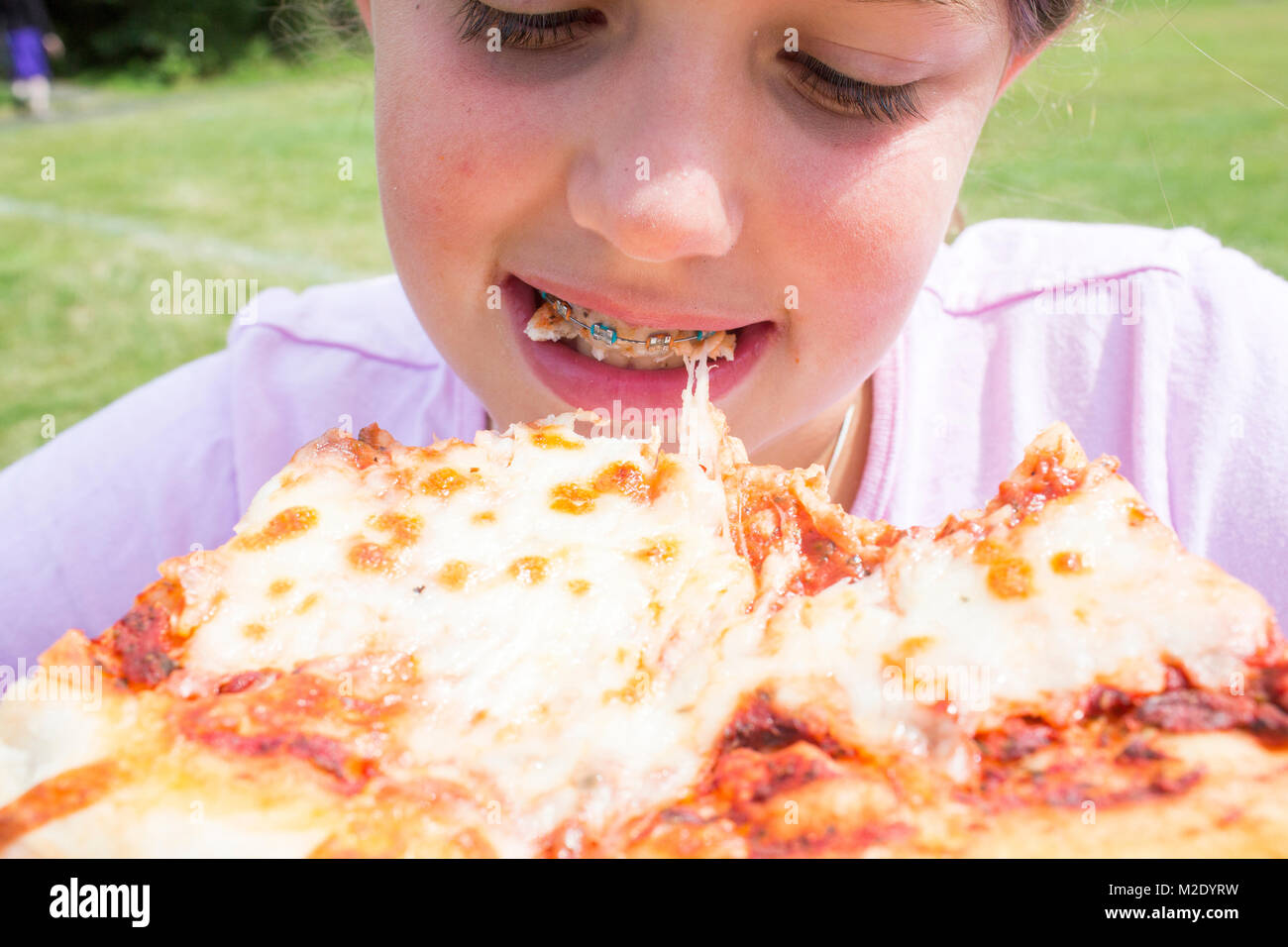 Close up of Caucasian girl with braces biting pizza Stock Photo