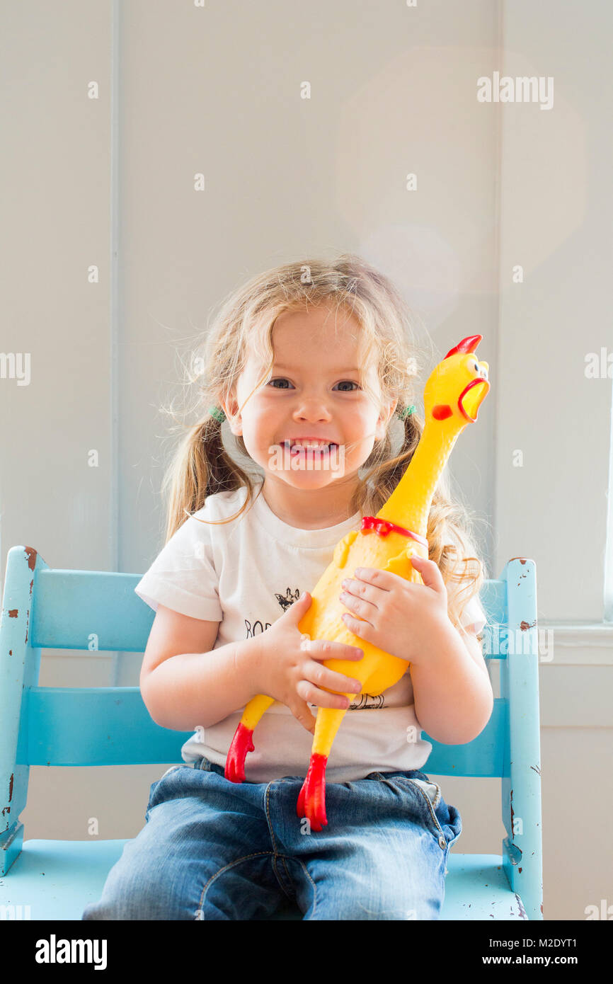 Smiling Caucasian girl holding rubber chicken Stock Photo