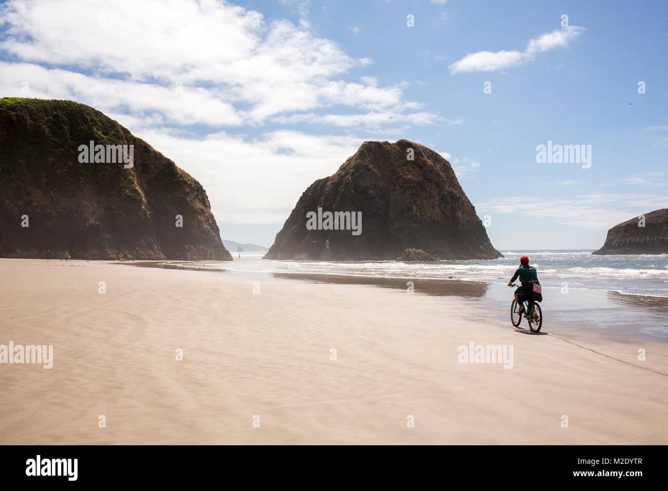Distant Caucasian woman riding bicycle on beach Stock Photo