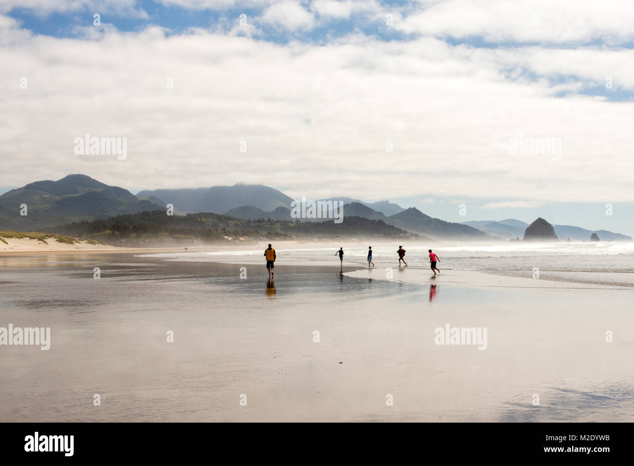 Distant people running on beach Stock Photo