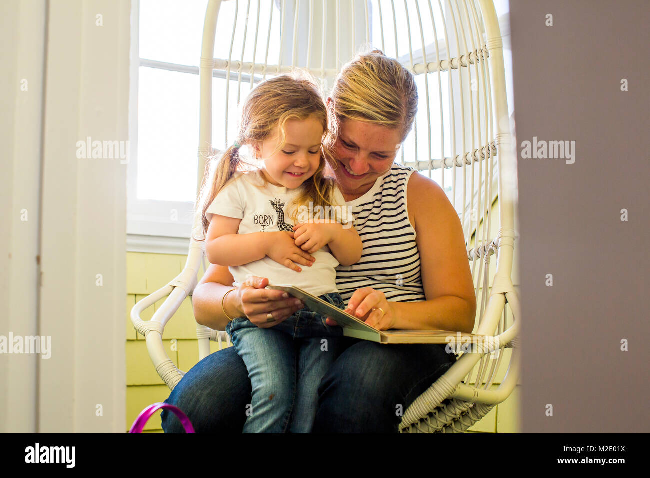 Caucasian mother reading book to daughter on lap Stock Photo