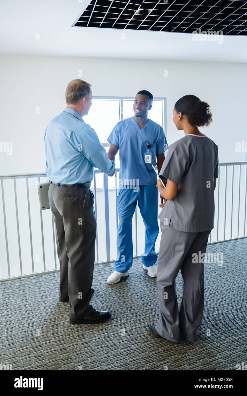 Doctor and nurse shaking hands near railing Stock Photo