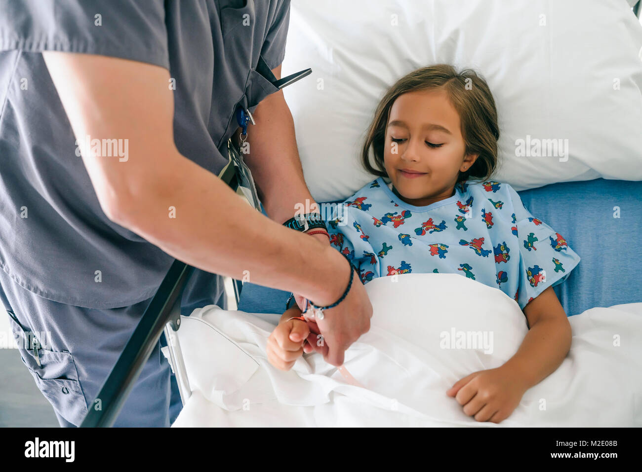 Doctor holding hand of girl in hospital bed Stock Photo