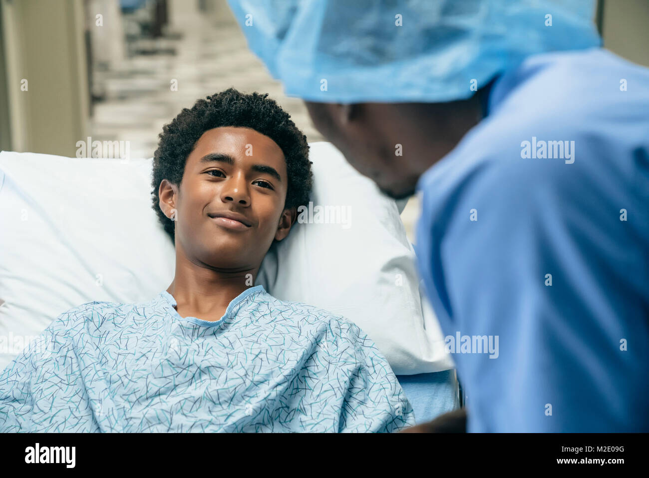 Black doctor talking to boy in hospital bed Stock Photo