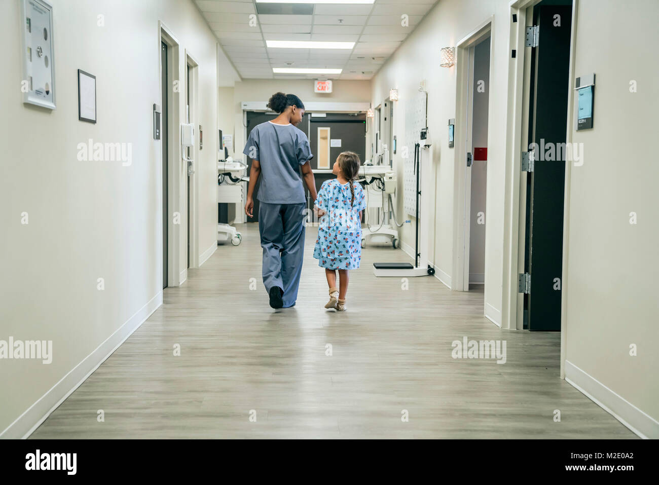Nurse walking with girl in hospital corridor Stock Photo
