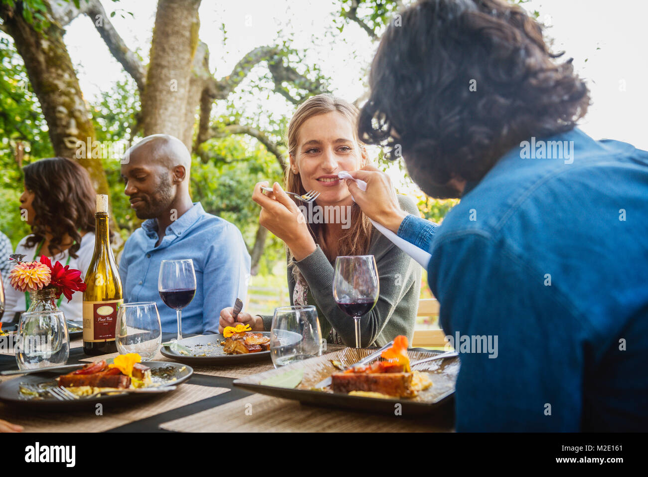 Man feeding food to woman at party outdoors Stock Photo