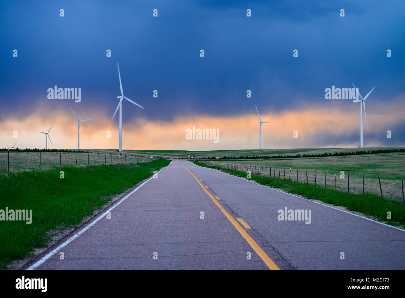 Wind turbines near road at sunset Stock Photo