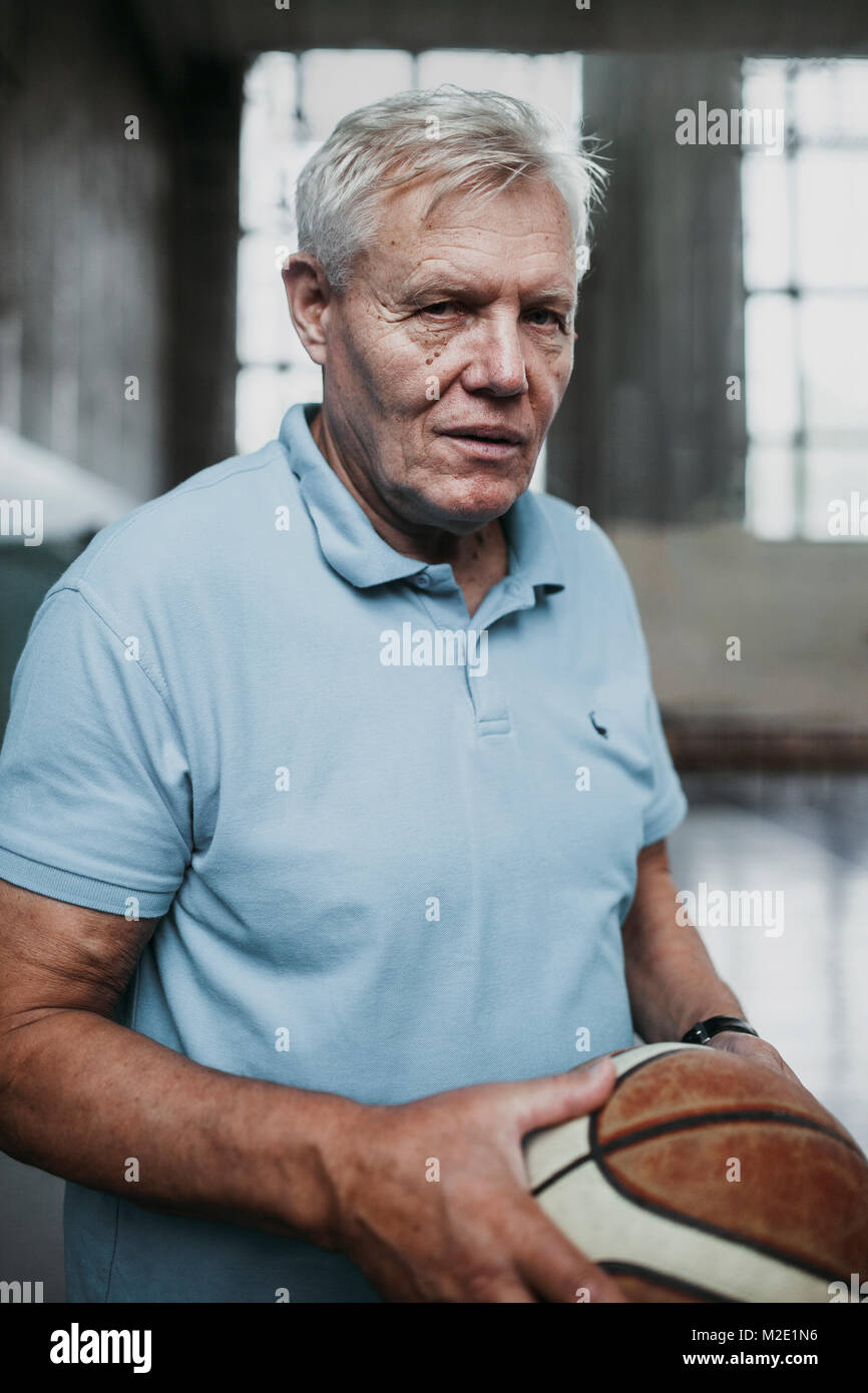 Portrait of serious Caucasian man holding basketball in gymnasium Stock Photo