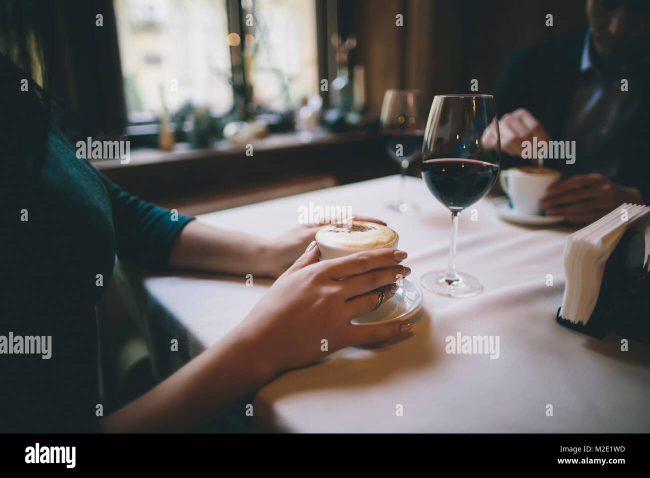 Hands of Caucasian couple drinking coffee and wine Stock Photo