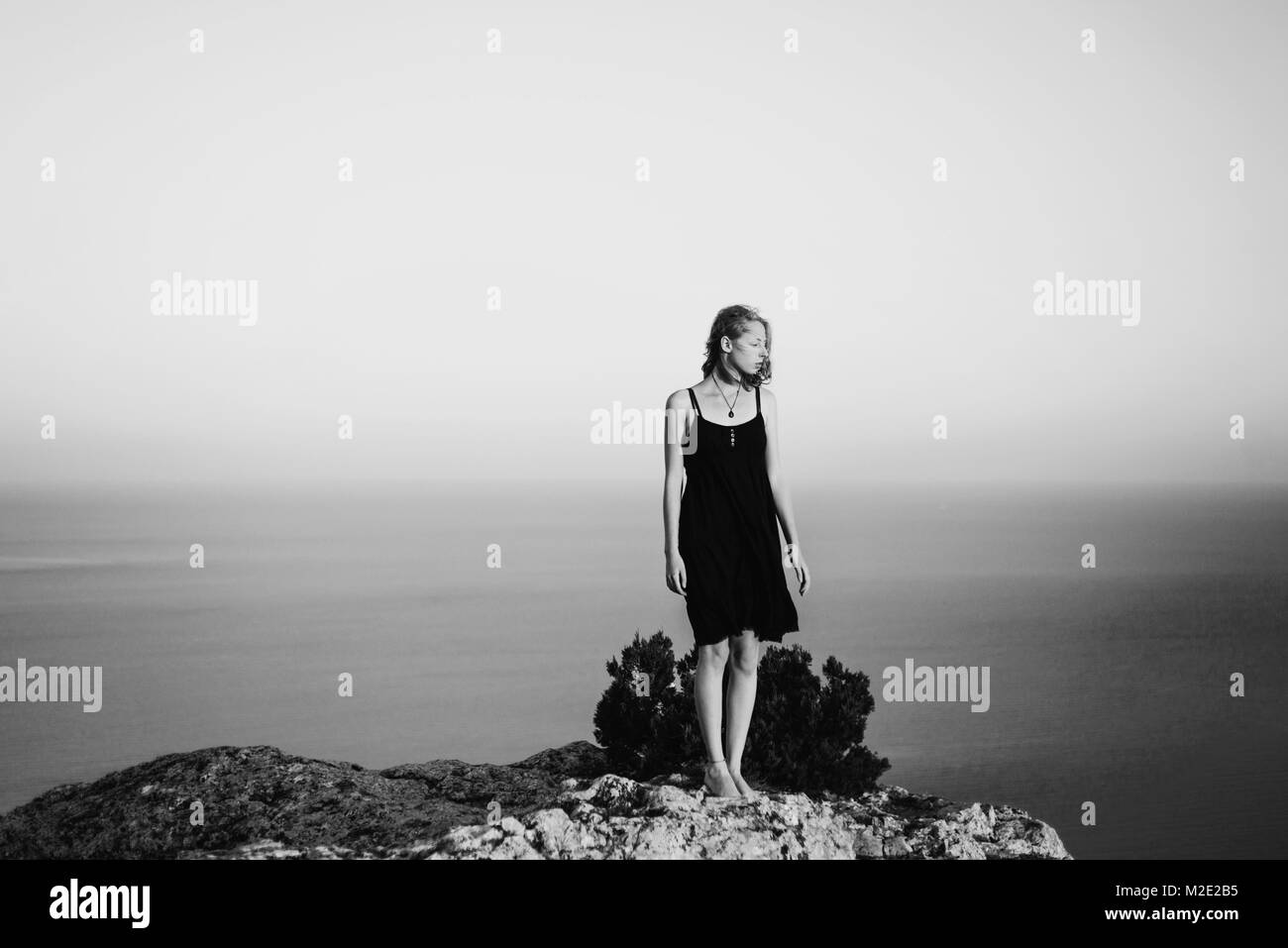 Caucasian woman standing on rock near ocean Stock Photo - Alamy