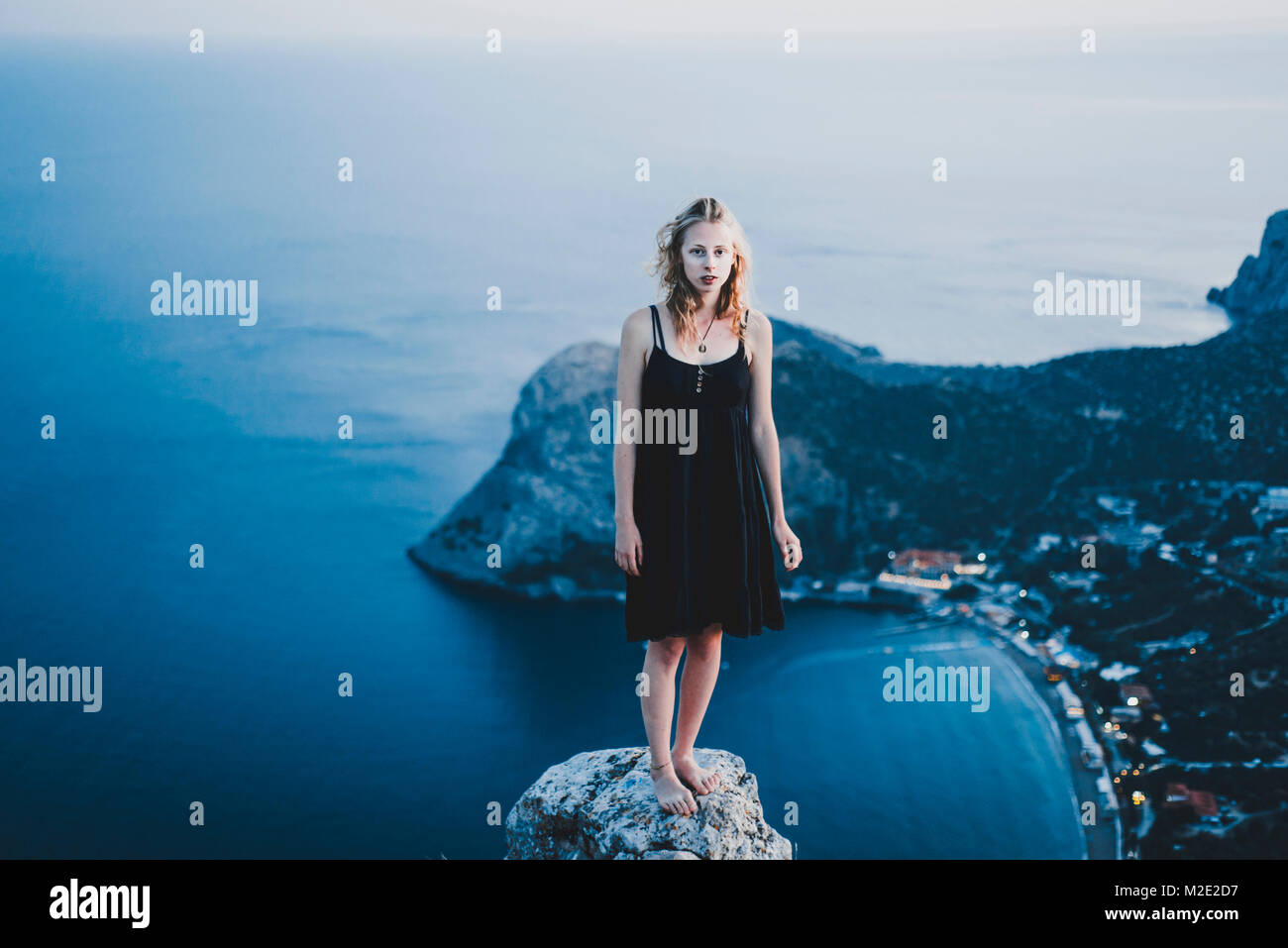 Caucasian woman standing on rock near ocean Stock Photo