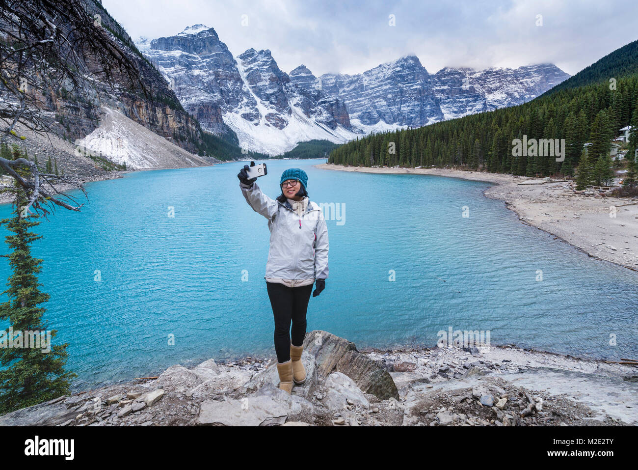Asian woman posing for cell phone selfie at mountain lake Stock Photo