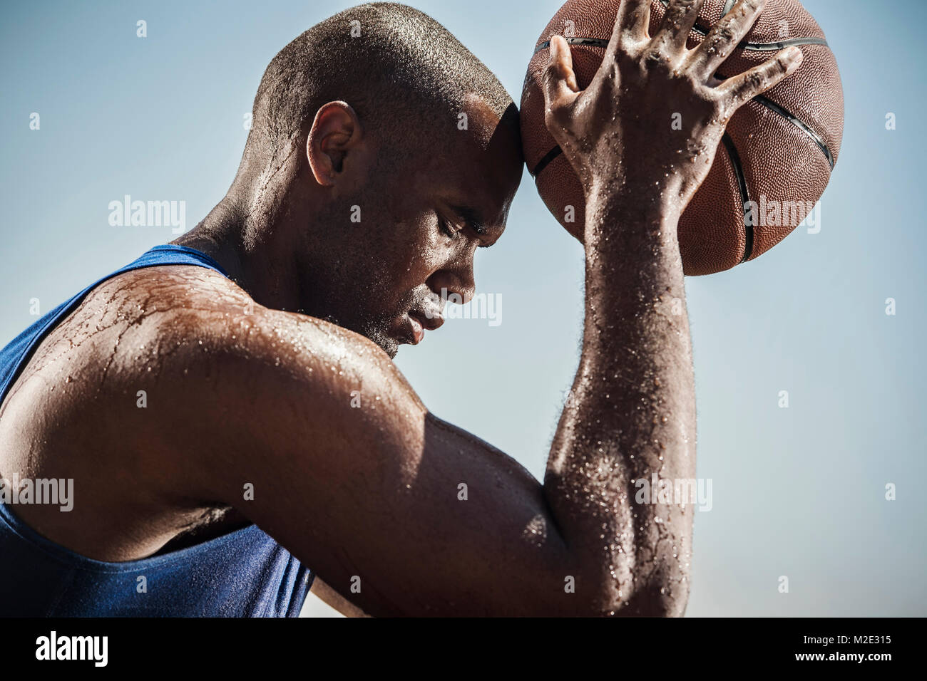 Portrait of sweating Black man touching forehead with basketball Stock Photo