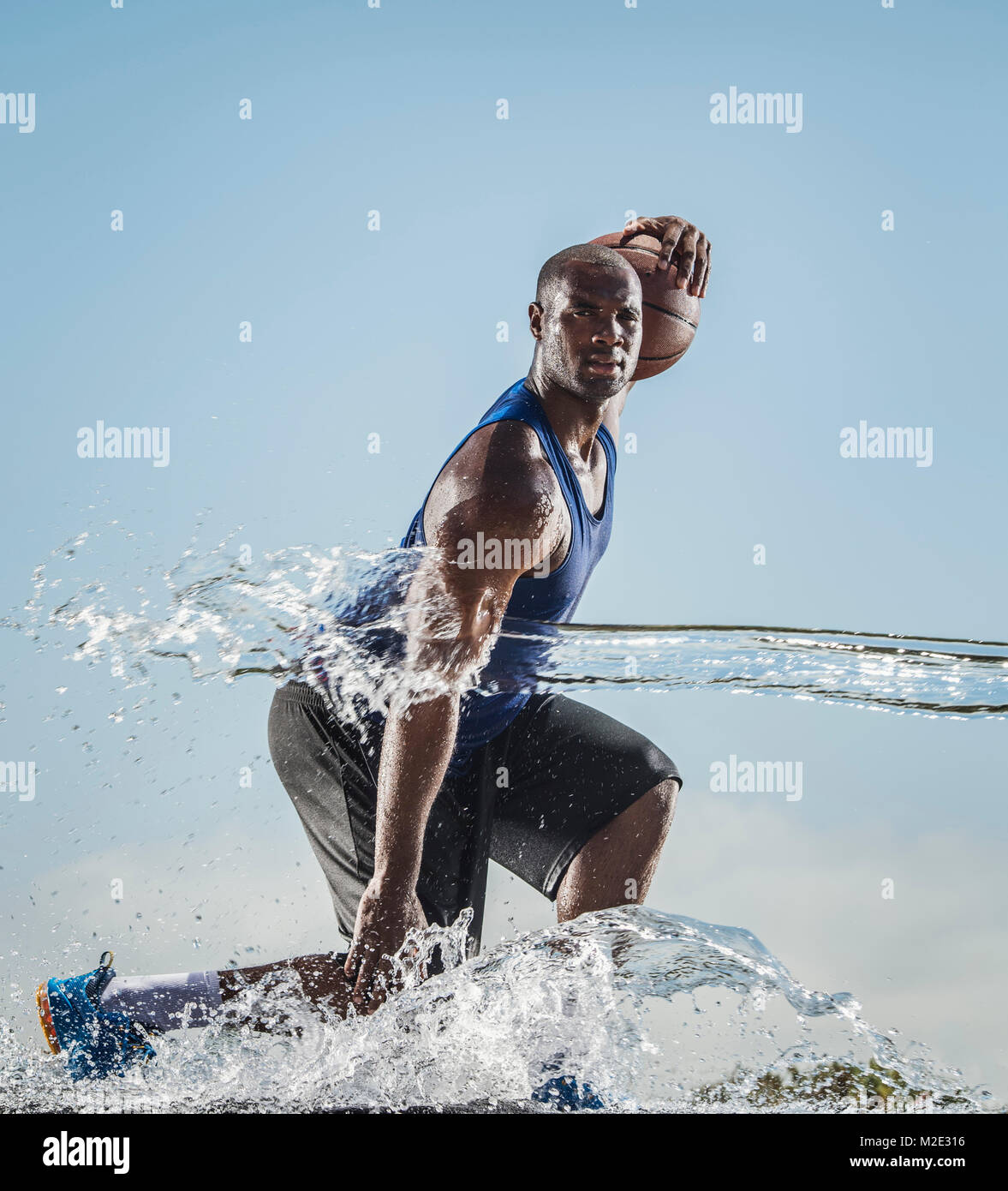 Water splashing on Black man dribbling basketball Stock Photo