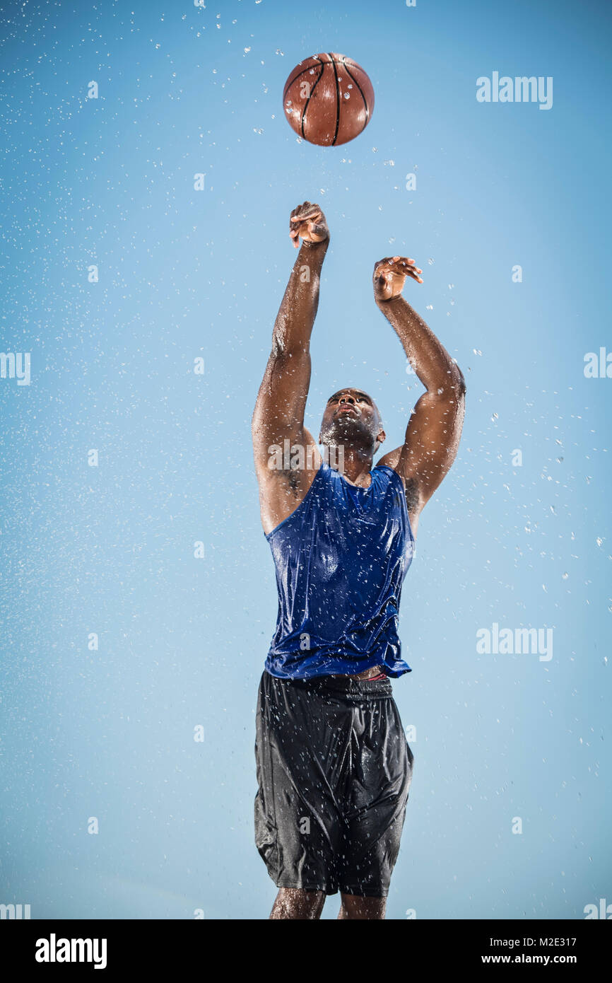 Water splashing on Black man shooting basketball Stock Photo